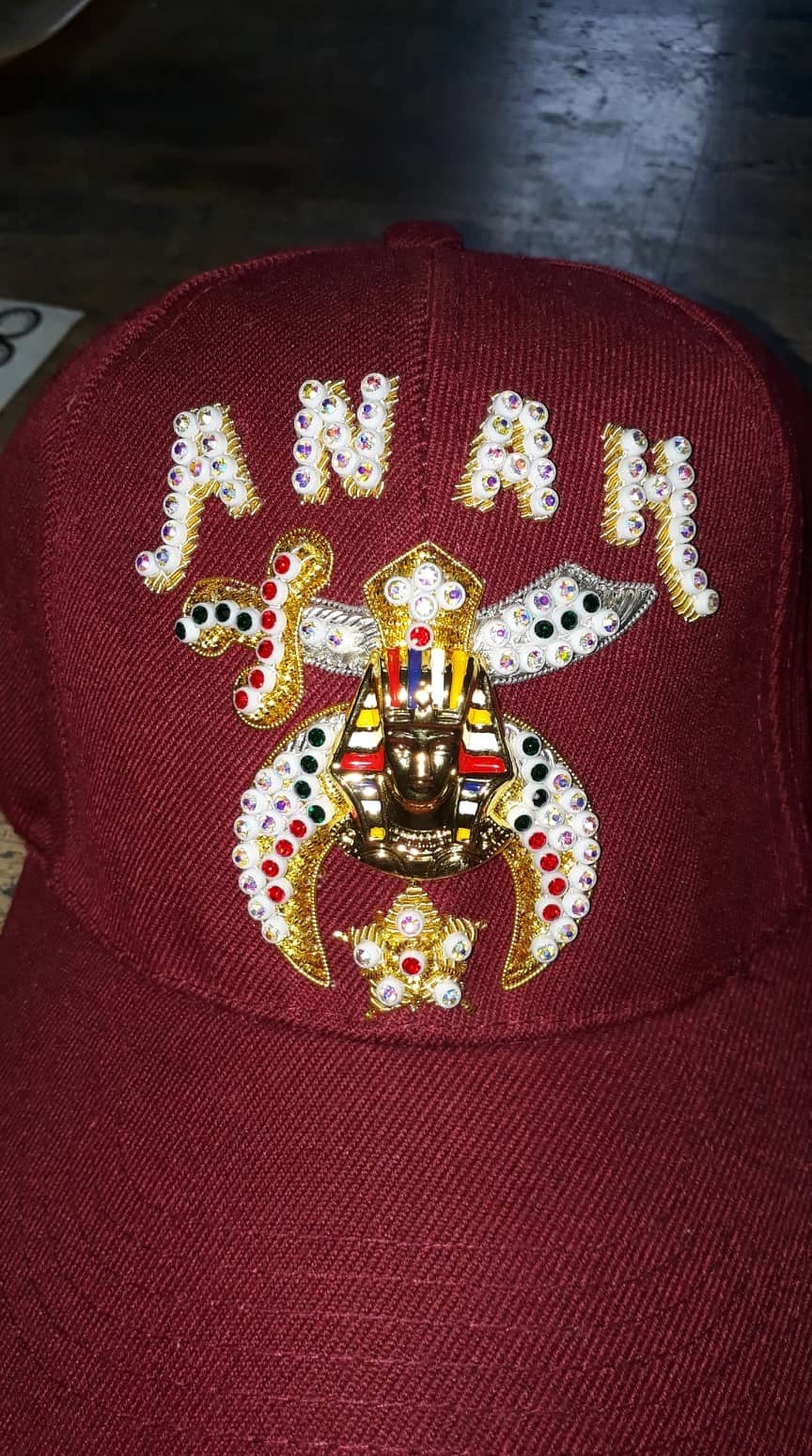 Burgundy jeweled Shriner cap with decorated lettering and central emblem