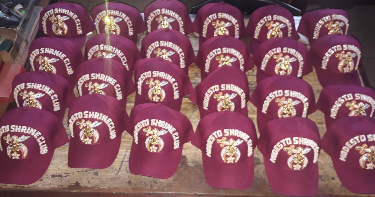 Group of burgundy Shriners club caps with jeweled club lettering and Shrine emblems; example designs