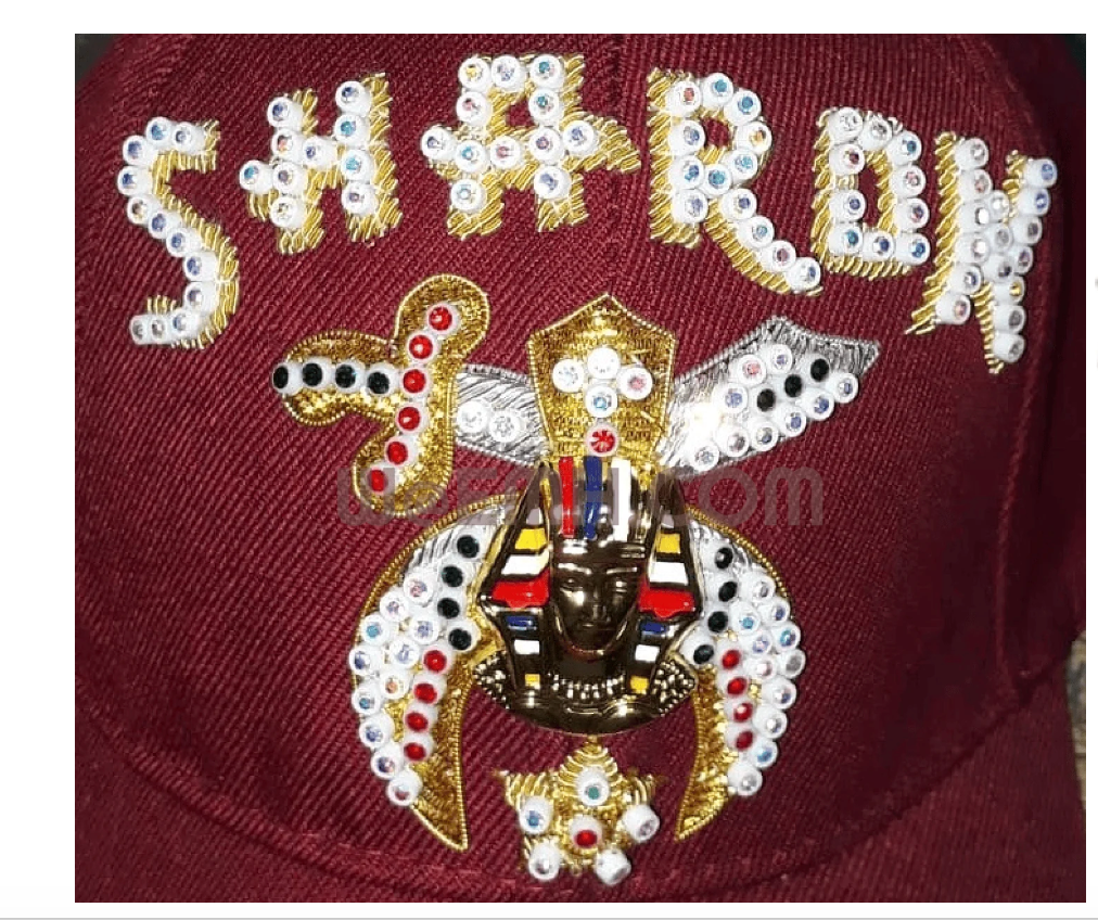 Close-up of burgundy Shriner cap with jeweled lettering and emblem